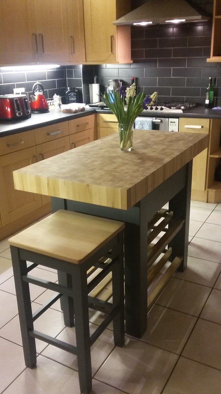 Kitchen with wooden island and stools, featuring a vase of flowers on the island.