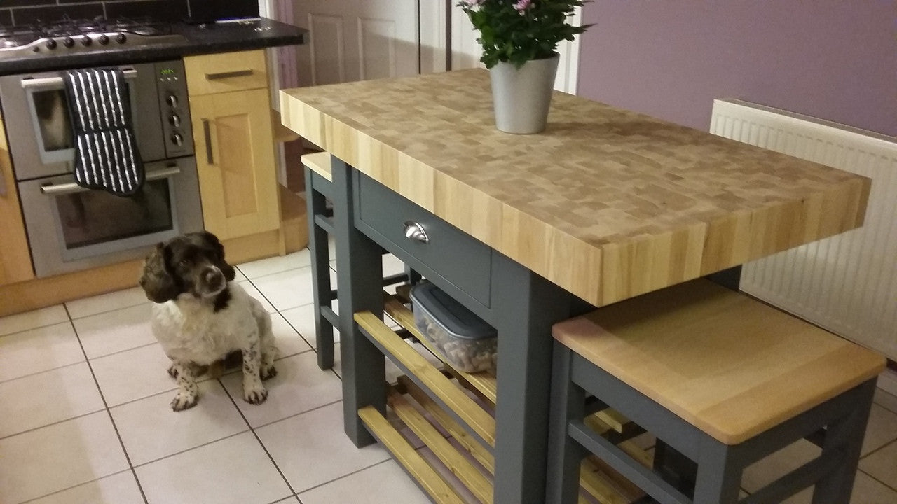 Kitchen island with wooden top and stools, dog standing nearby